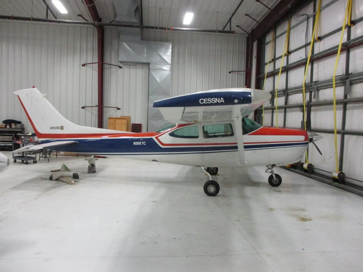 A white and blue Cessna aircraft is parked inside a hangar.