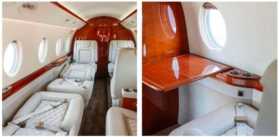 Interior view of the aircraft cabin with white leather seats and wooden tables and accents.