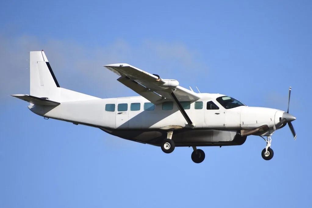 A white Cessna Caravan is shown in flight against a blue sky.