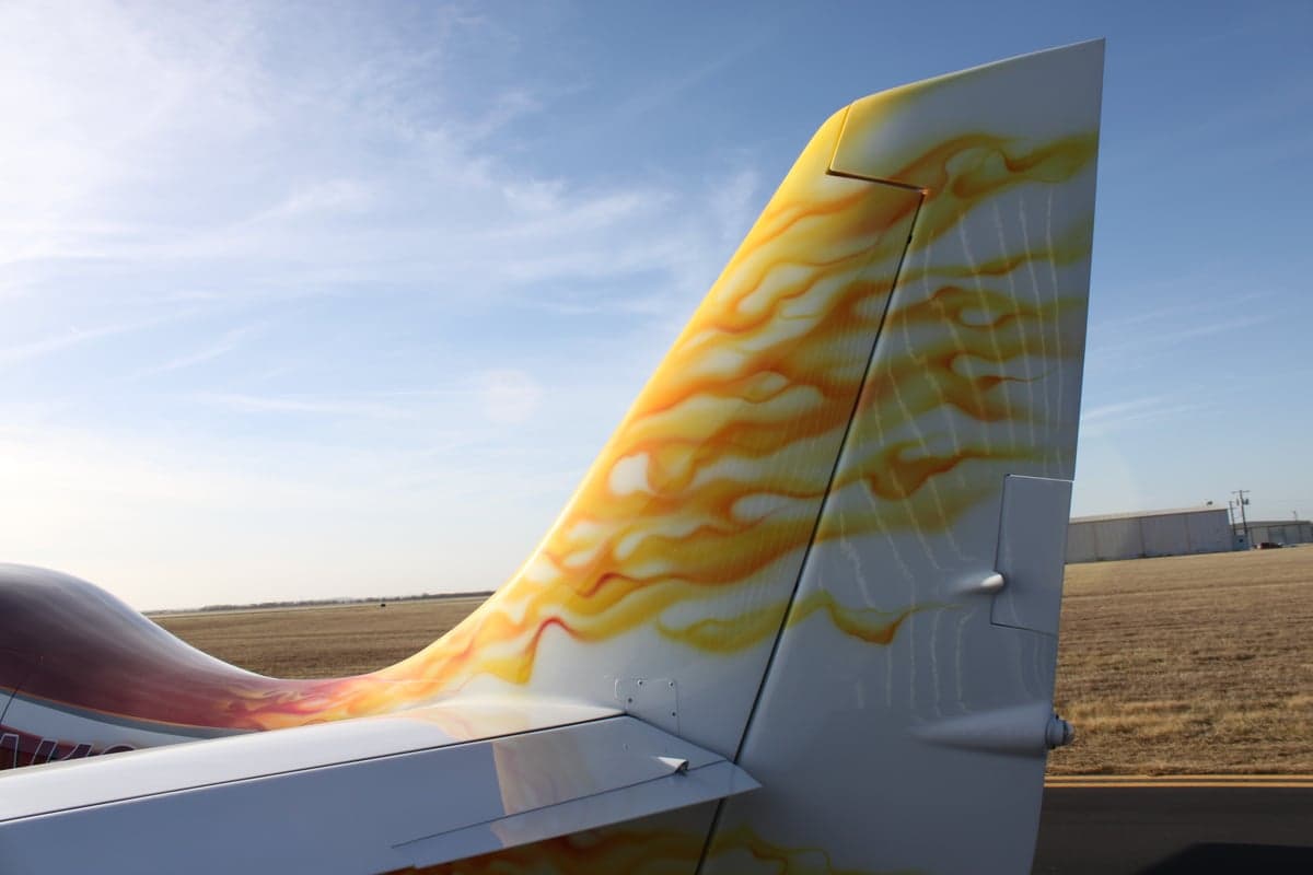 The tail of the aircraft features a flame design against a blue sky.