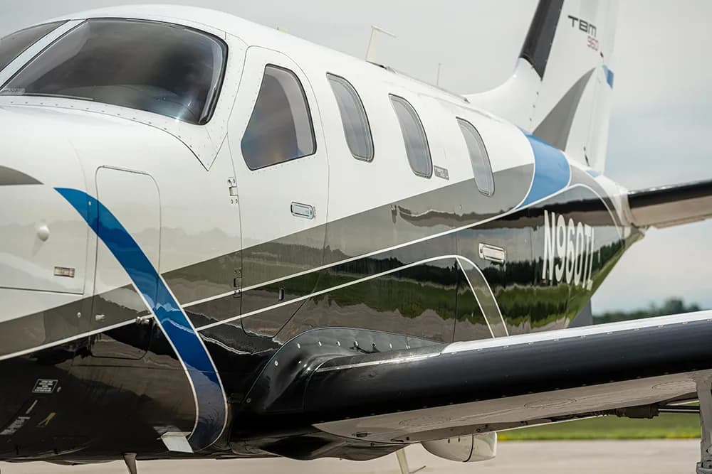 A close-up side view of the fuselage of a white, blue, and black TBM 960 aircraft with registration N960TL.
