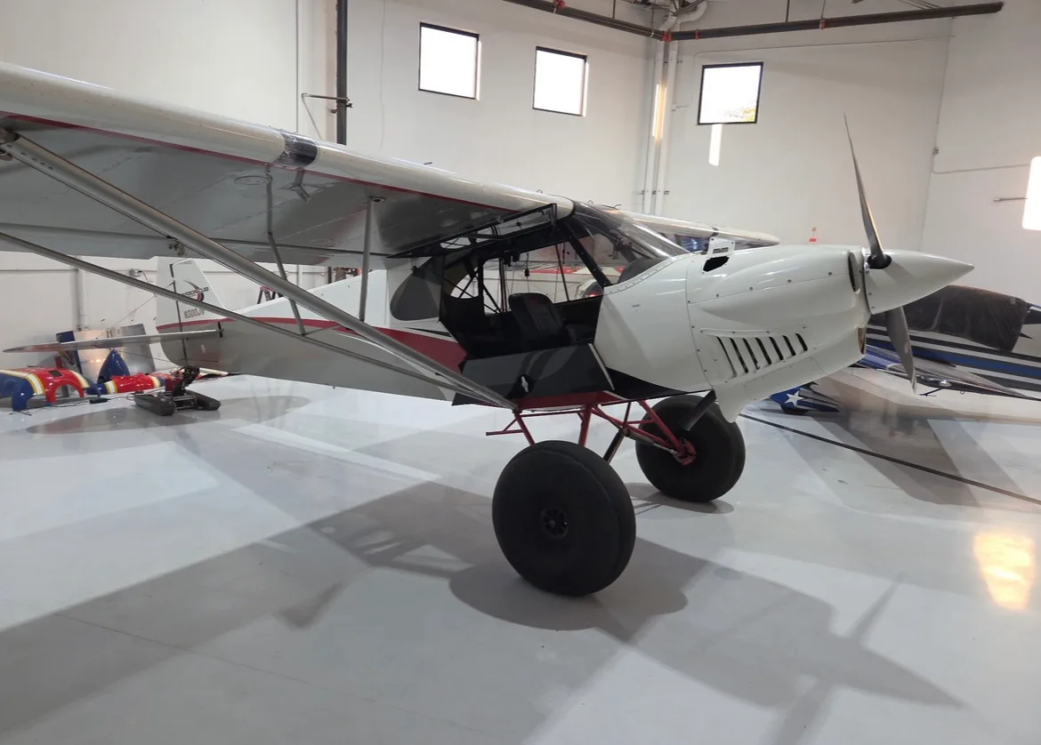 A Carbon Cub FX3 in a hangar, showing the front and side.