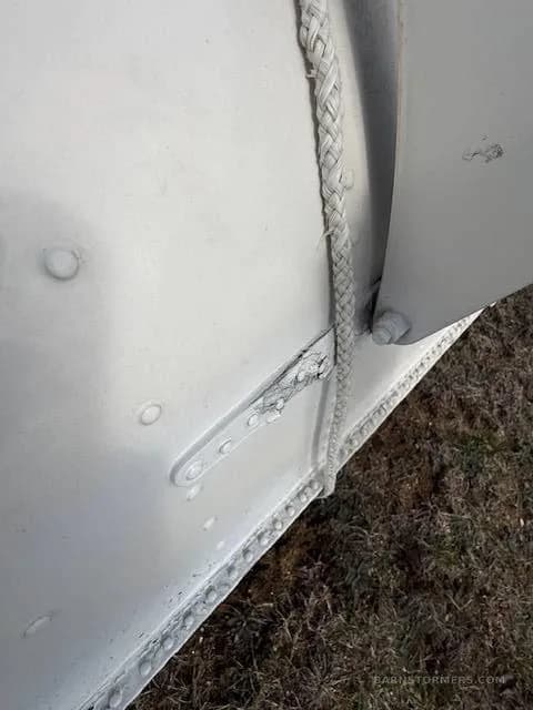 An extreme close-up of a white aircraft float showing a braided rope and a hinge mechanism.