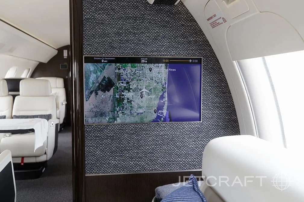 An aircraft cabin wall with a large screen displaying a map of Florida, showing a flight path.