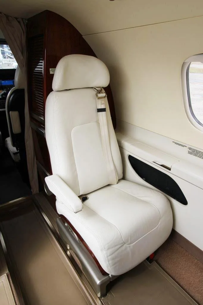 A close-up of a Phenom 300E cabin seat shows the leather upholstery and design details.