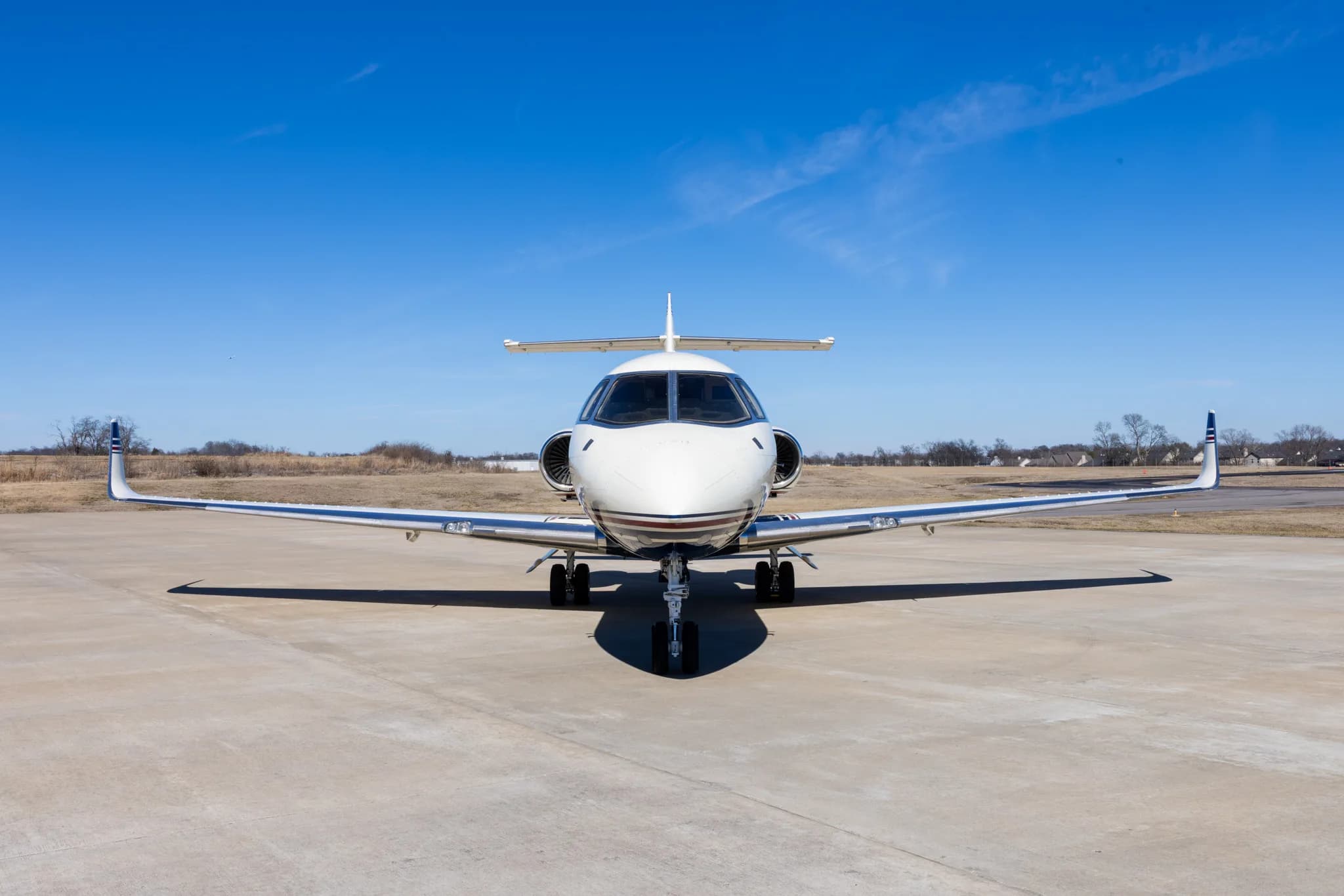 A head-on view of the white and blue business jet, N800UK, parked on a concrete tarmac.