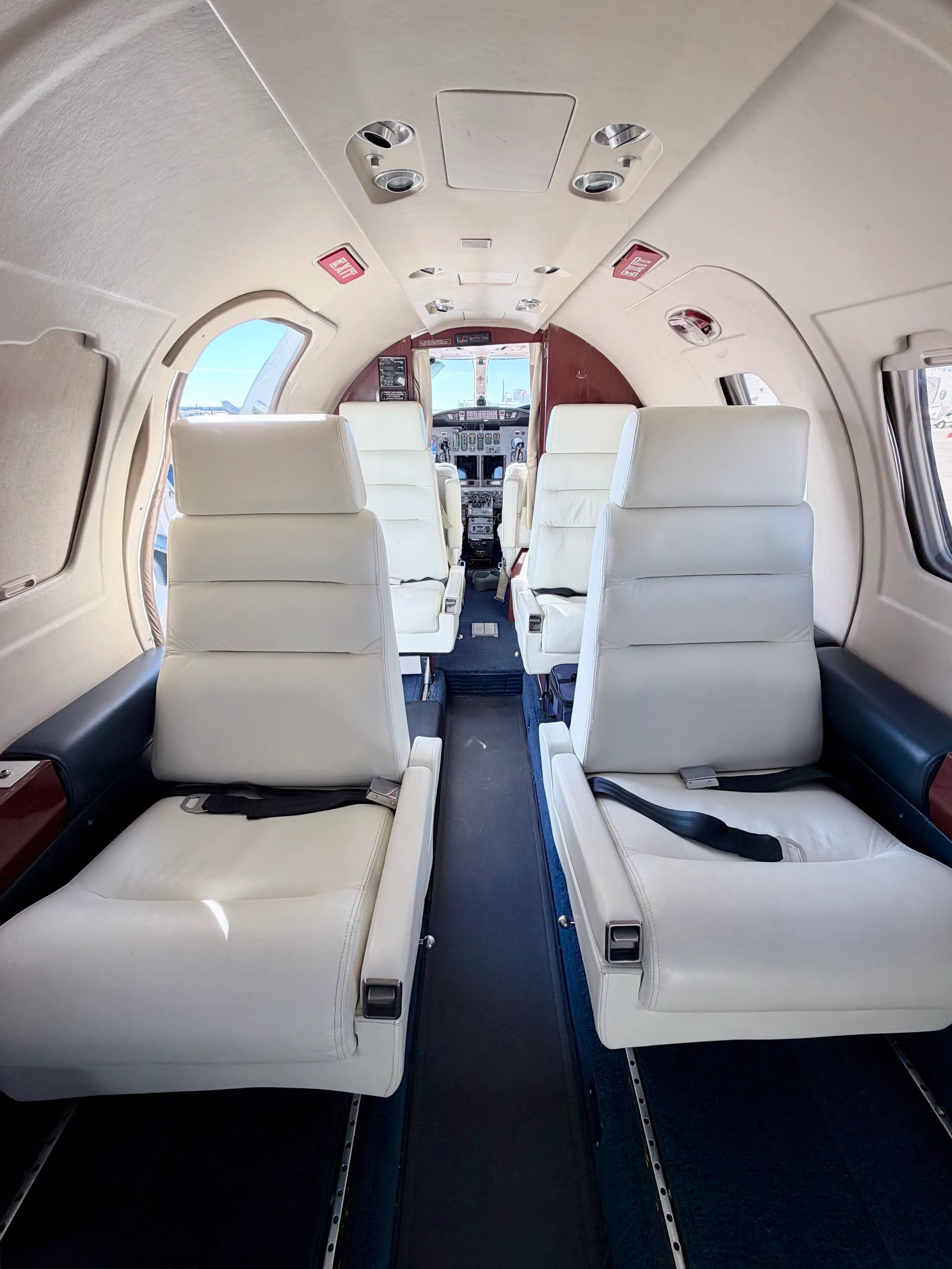 View looking forward inside the aircraft cabin, showing rows of light-colored leather passenger seats.
