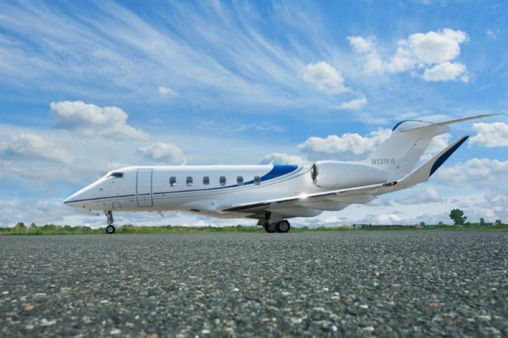 Side view of a white and blue Bombardier Challenger 350 on the tarmac.