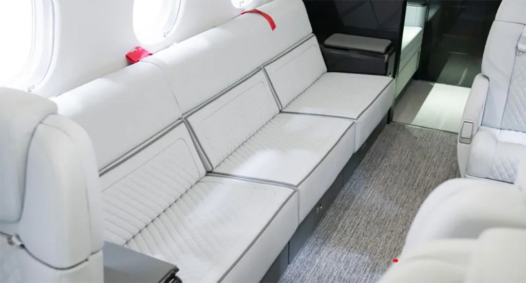 A close-up view of the light grey quilted couch-style seating in the aircraft's cabin.
