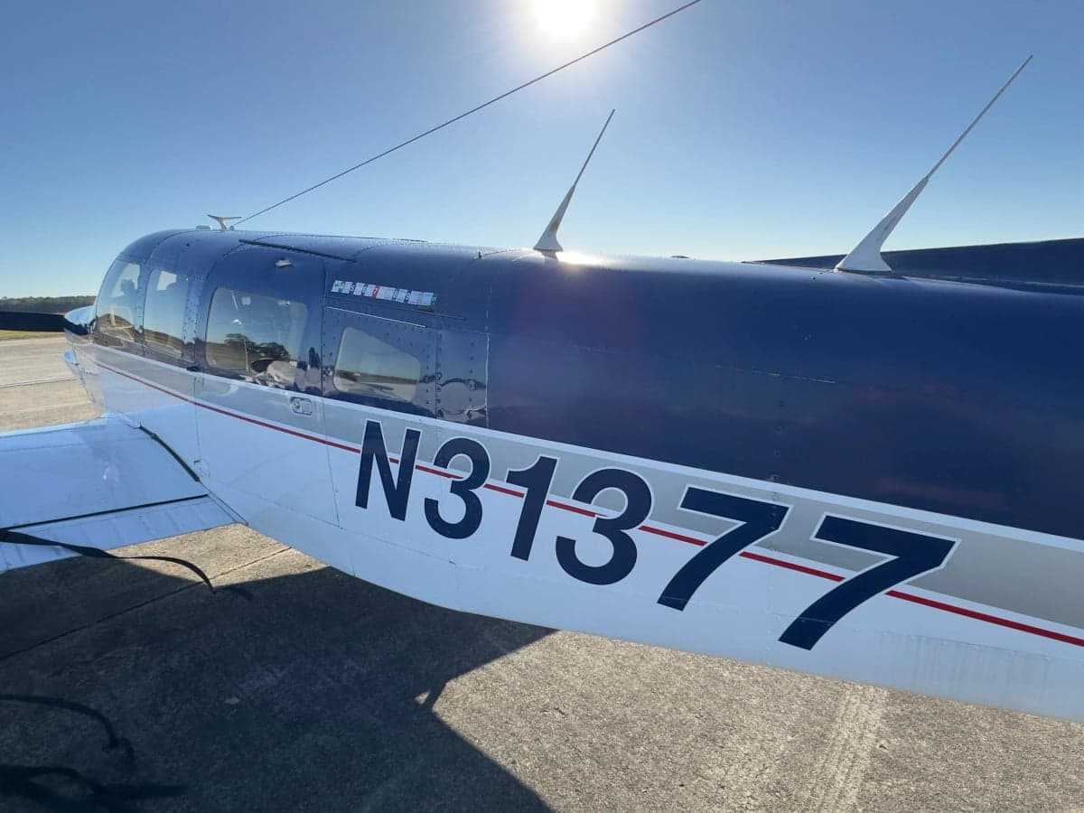 Close-up of the fuselage and registration N31377 of a Piper Cherokee aircraft.