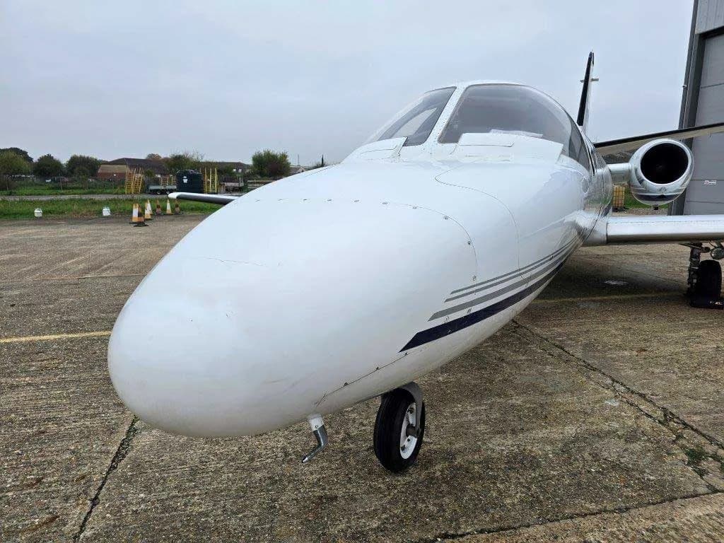 A close-up view of the white nose and front landing gear of a Cessna Citation jet.