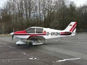 Side view of a white and red aircraft with German flag on the tail, parked on the tarmac.