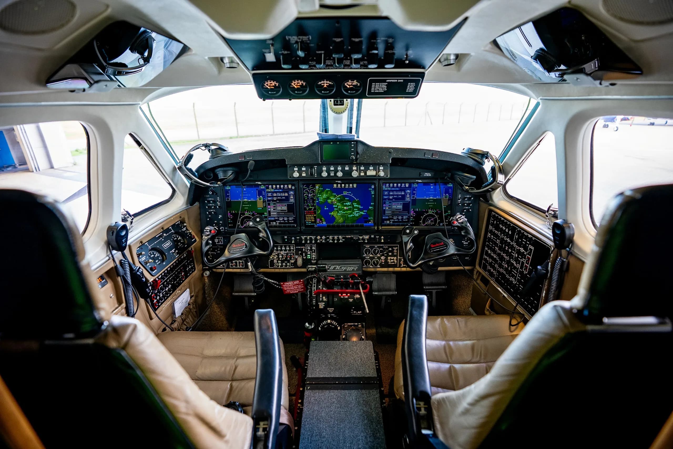 The modern glass cockpit of a Beechcraft King Air 260, featuring multiple digital displays and control yokes.