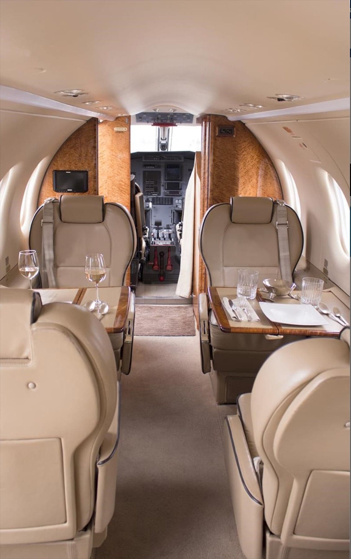 Interior view of an aircraft cabin with seats, tables, and glassware.