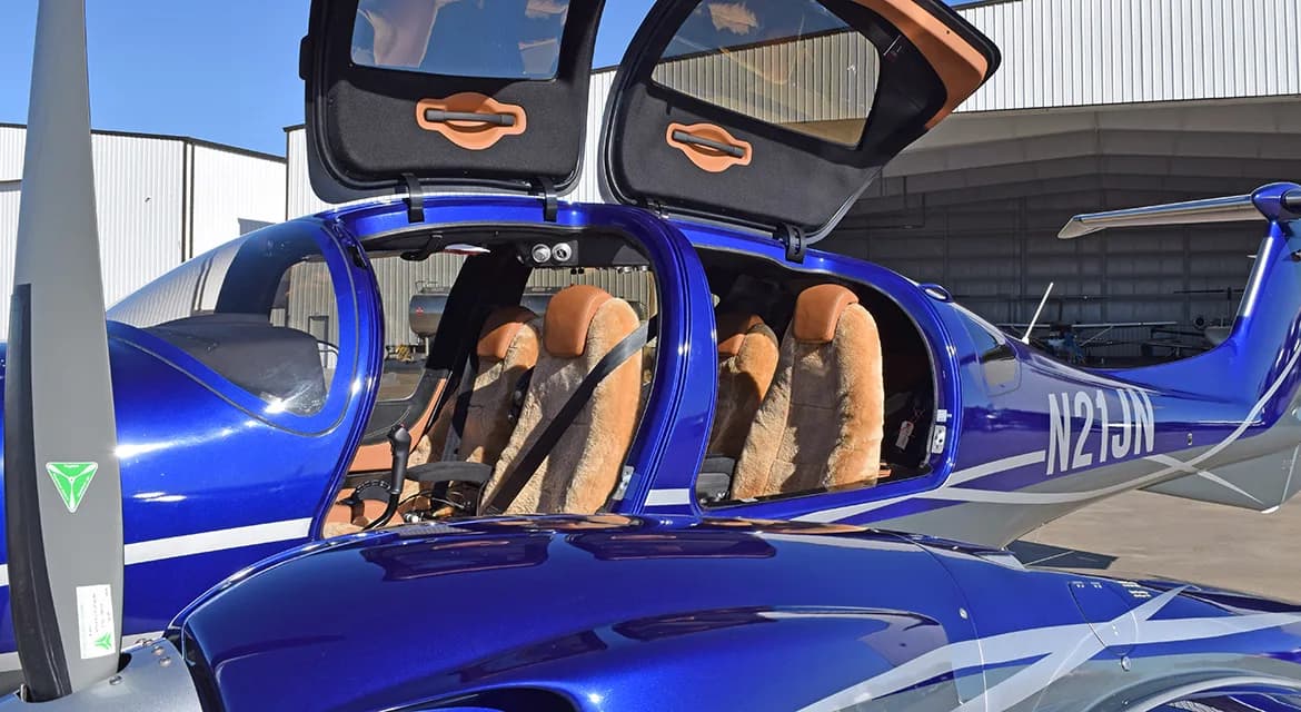 A Diamond DA62 aircraft with its doors open, revealing the tan leather interior.