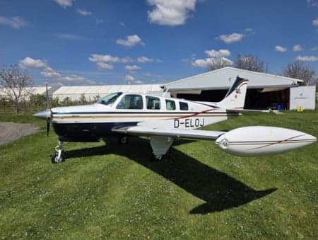 A Beechcraft Bonanza with registration D-ELOJ parked on grass.