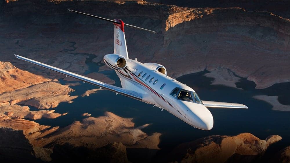 A Citation CJ4 flying over a canyon landscape.