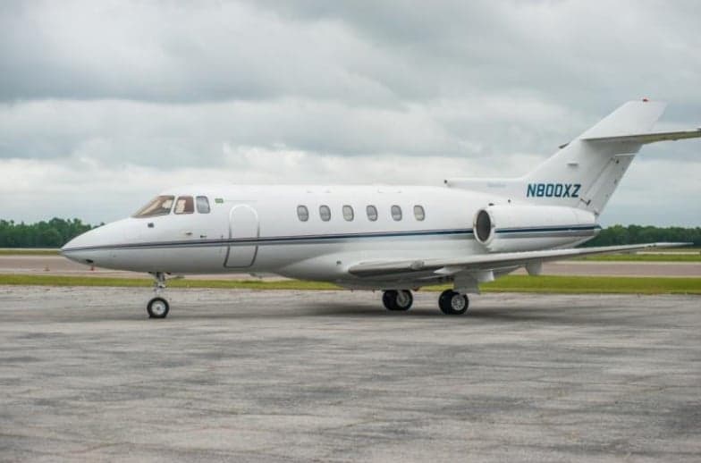 A white jet with blue stripes sits on the tarmac.