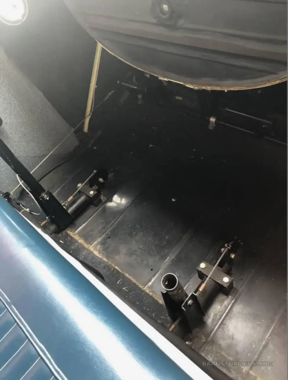 The floor and rudder pedals of an aircraft cabin, with a blue seat visible at the bottom.