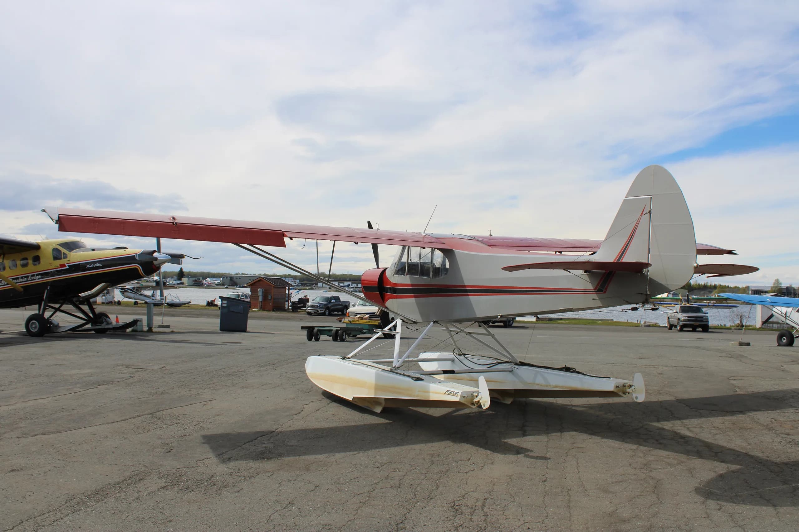 A red and silver float plane is parked on the tarmac, angled view.