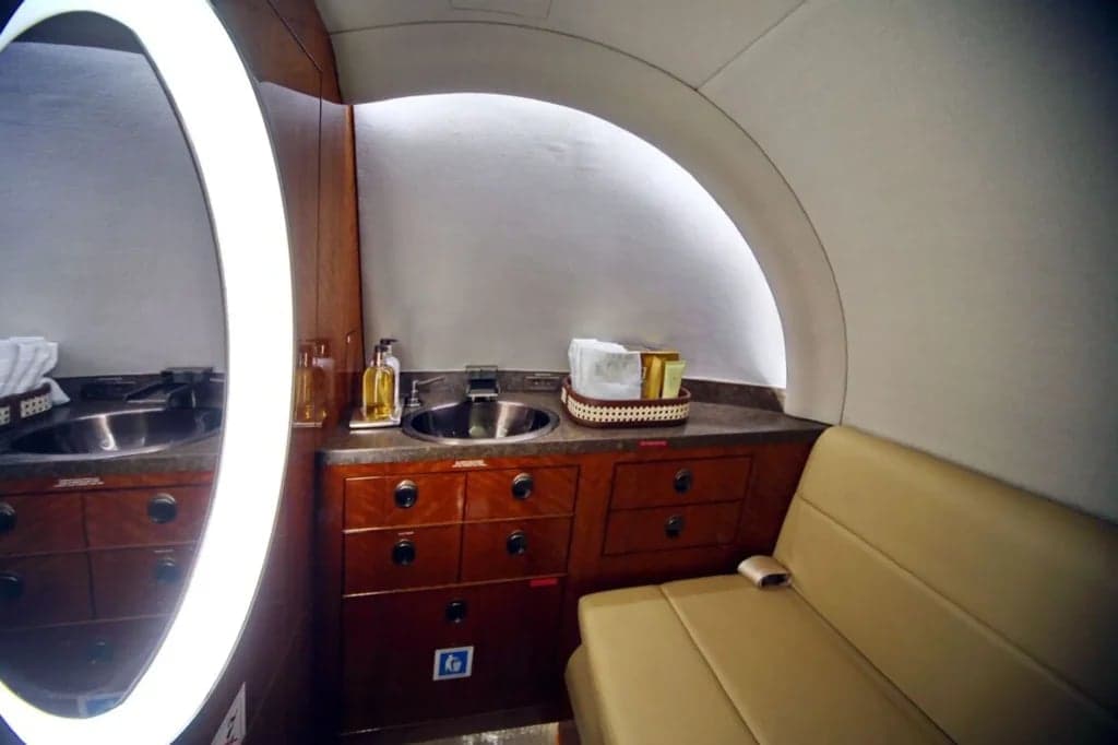A view of the aircraft's lavatory with a sink, mirror, and storage cabinets.