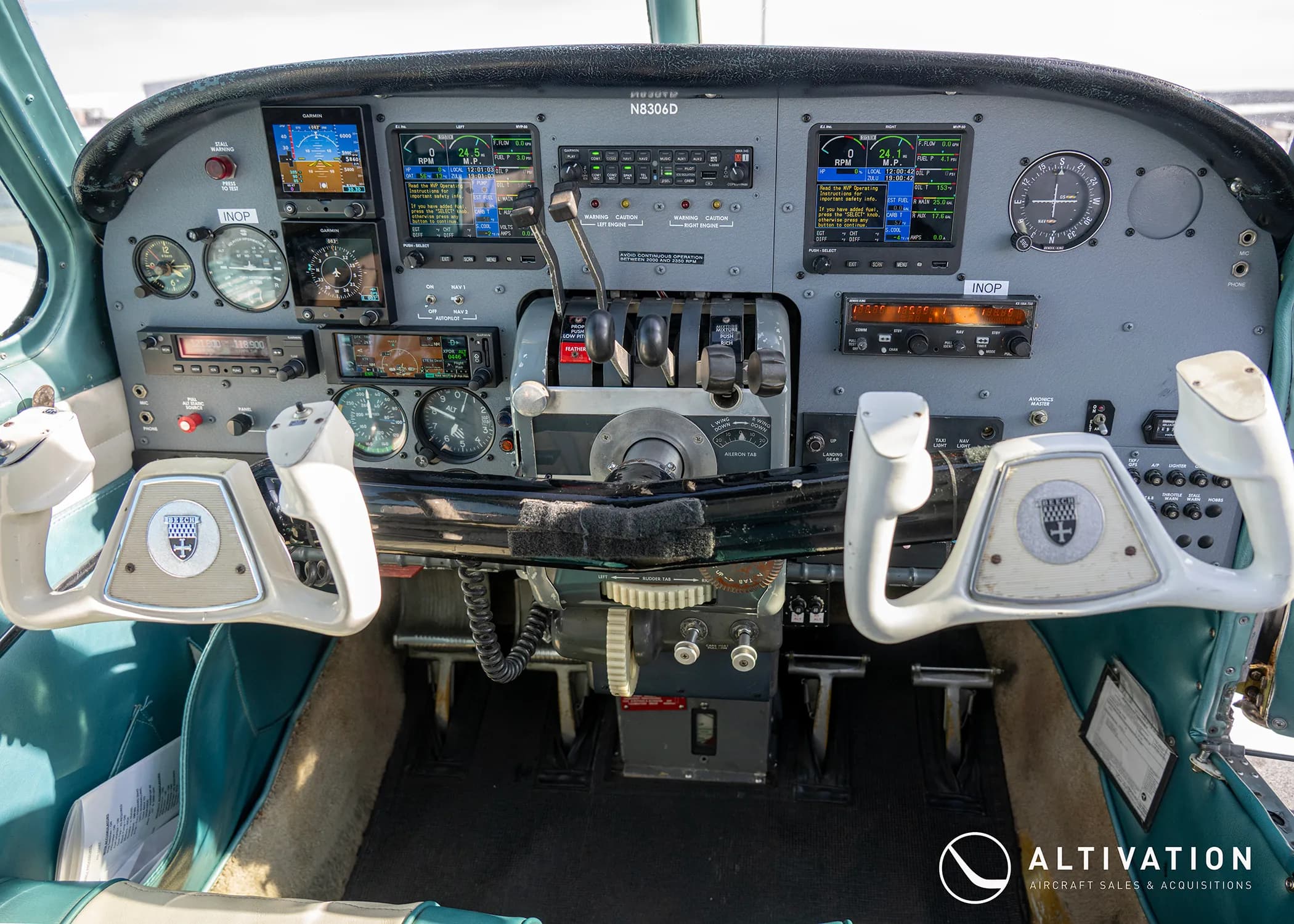 The cockpit of an aircraft, showing the instrument panel with multiple displays, gauges, and two control yokes.