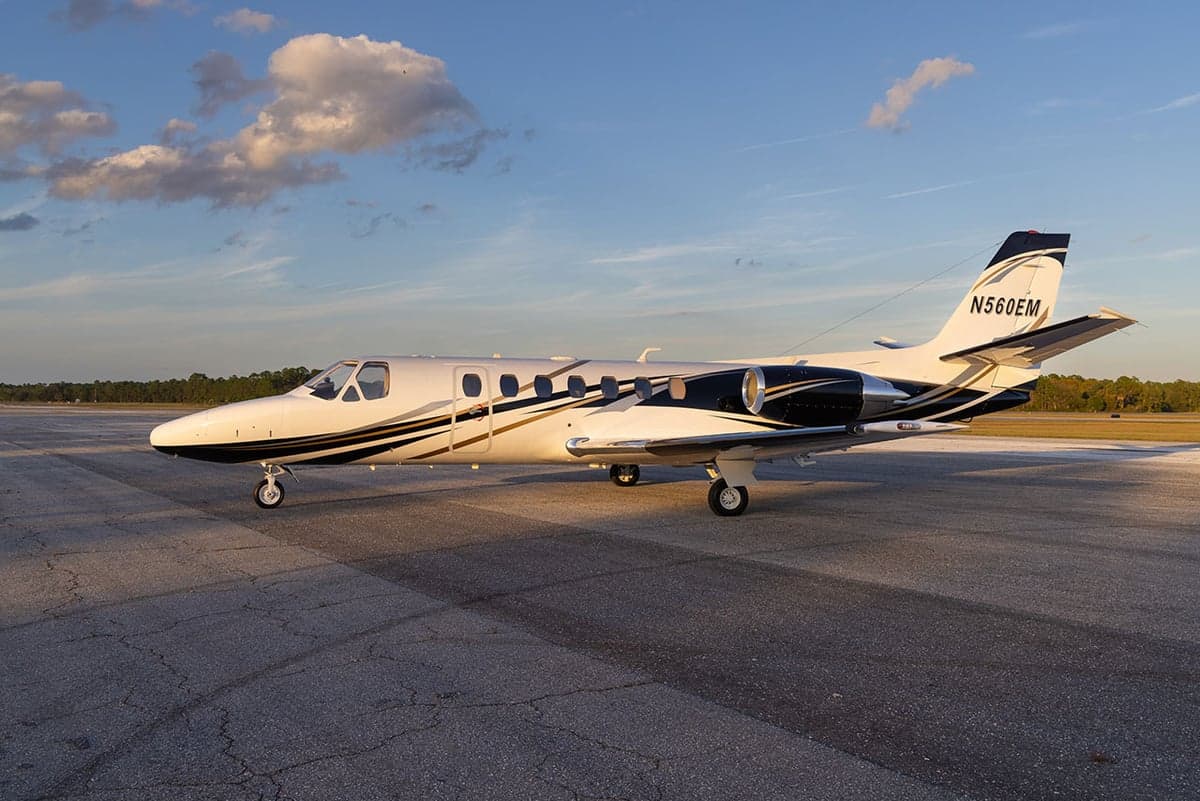Side view of the N560EM aircraft parked on the tarmac at sunset.