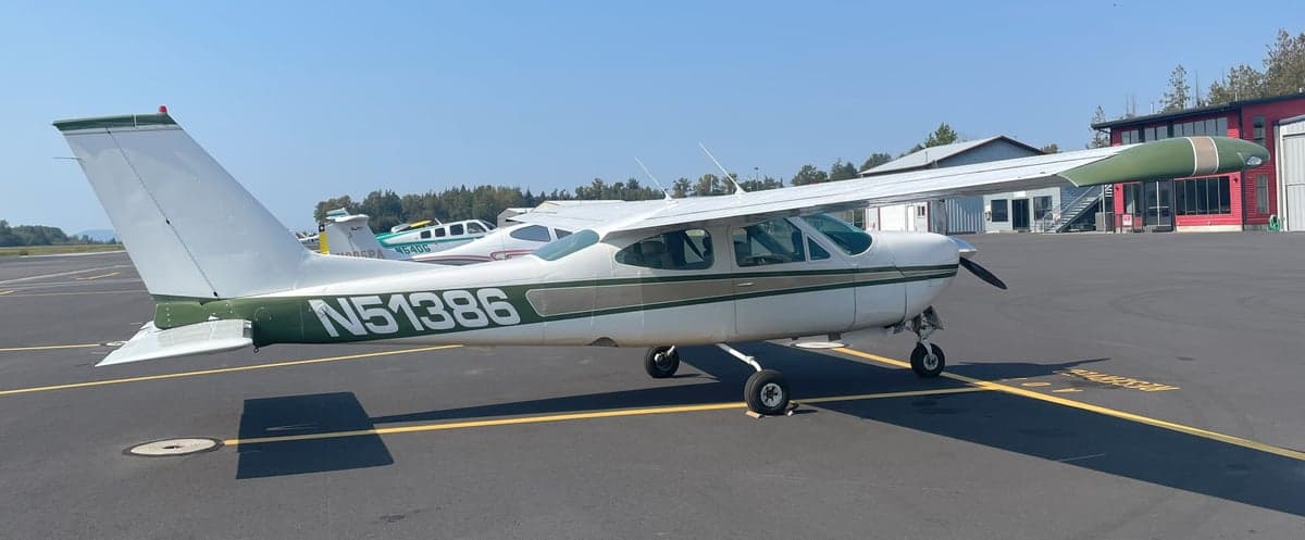 A white and green Cessna Cardinal RG II, registration N51386, is parked on the tarmac at an airport.