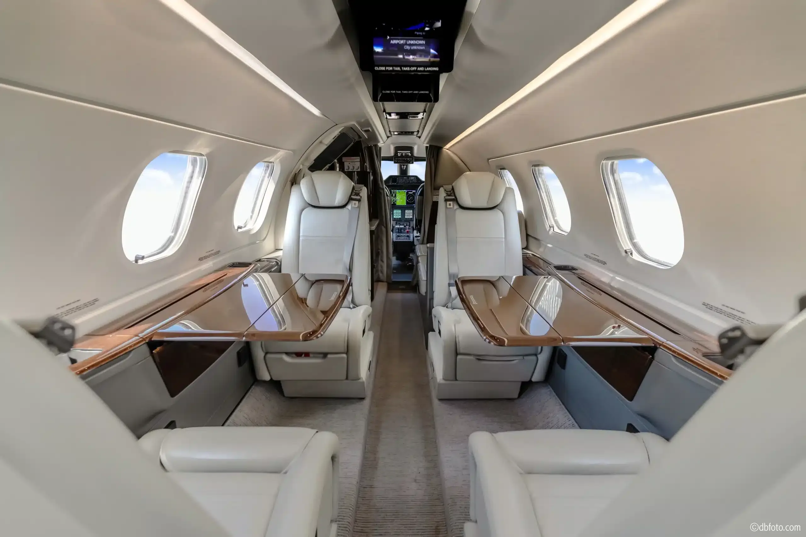 Aircraft cabin with leather seats and tables.