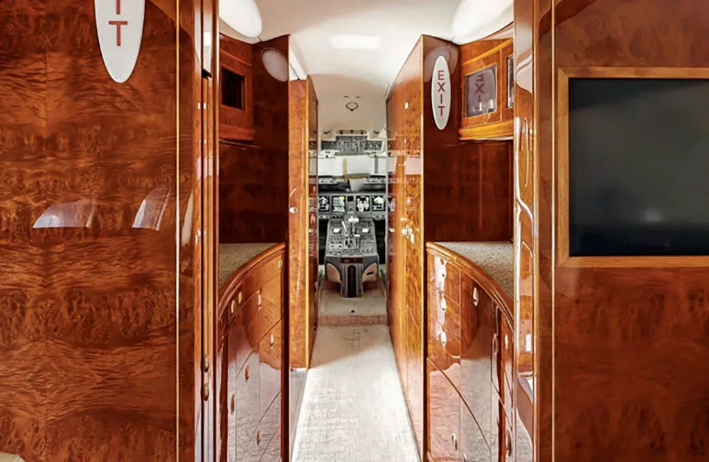 A view from the aircraft cabin looking into the cockpit, framed by rich, polished wood paneling.