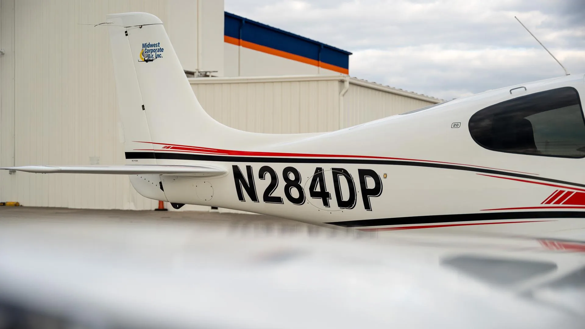A close-up of the tail section of the white Cirrus SR22 aircraft, showing the N284DP registration and "Midwest Corporate Air, Inc." logo.