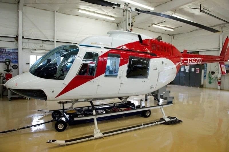A red and white Bell 407 helicopter in a hangar.