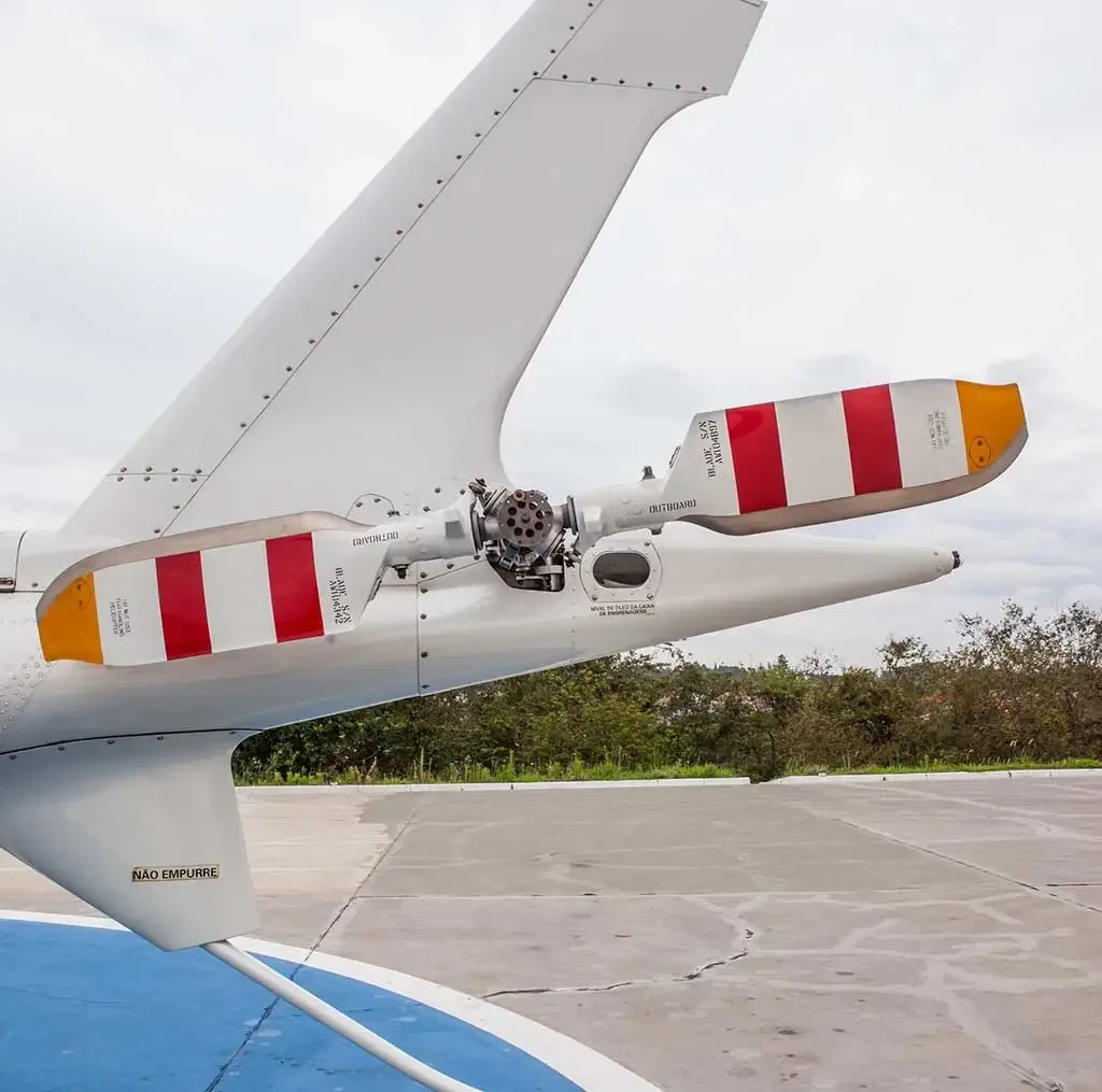 A close-up view of the helicopter's tail rotor, featuring red and white striped blades.