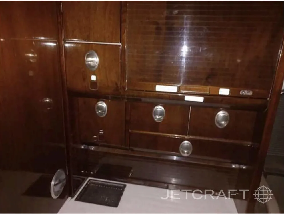 Dark wood aircraft cabinetry with silver handles and a small counter space is shown.