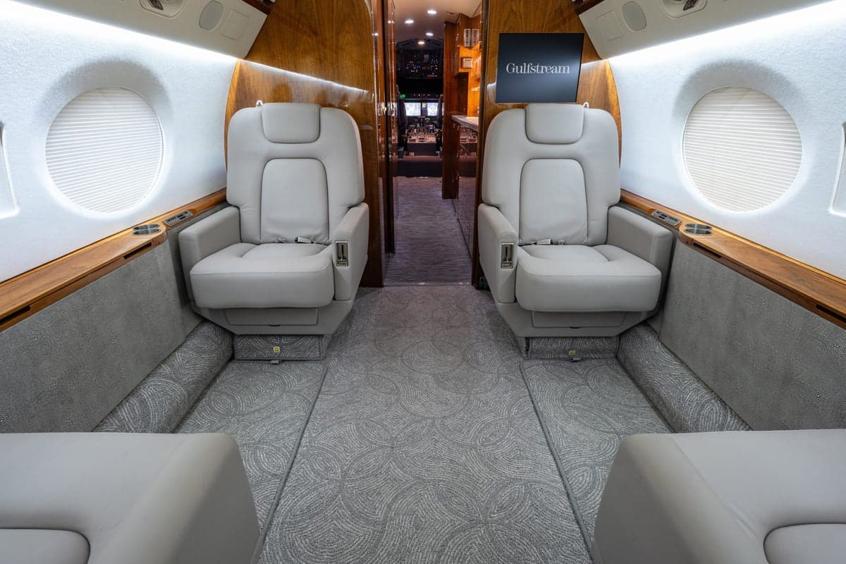 The aircraft's interior features comfortable seating and wood trim.