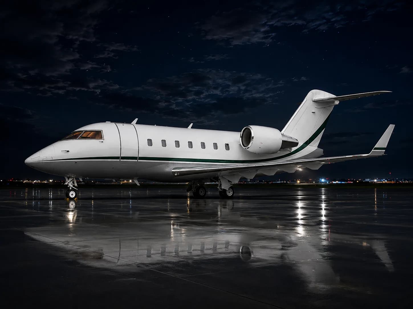 A white private jet with a green stripe sits on a wet tarmac at night, reflecting the airport lights.