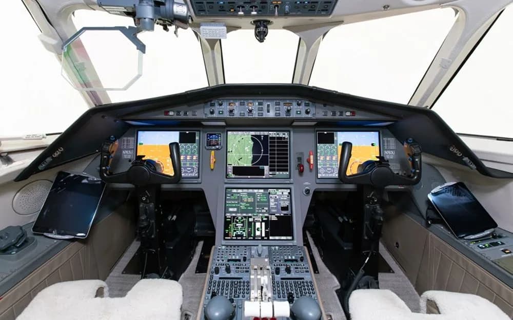 The modern cockpit of a Dassault Falcon 900EX, featuring multiple large digital displays and control yokes.