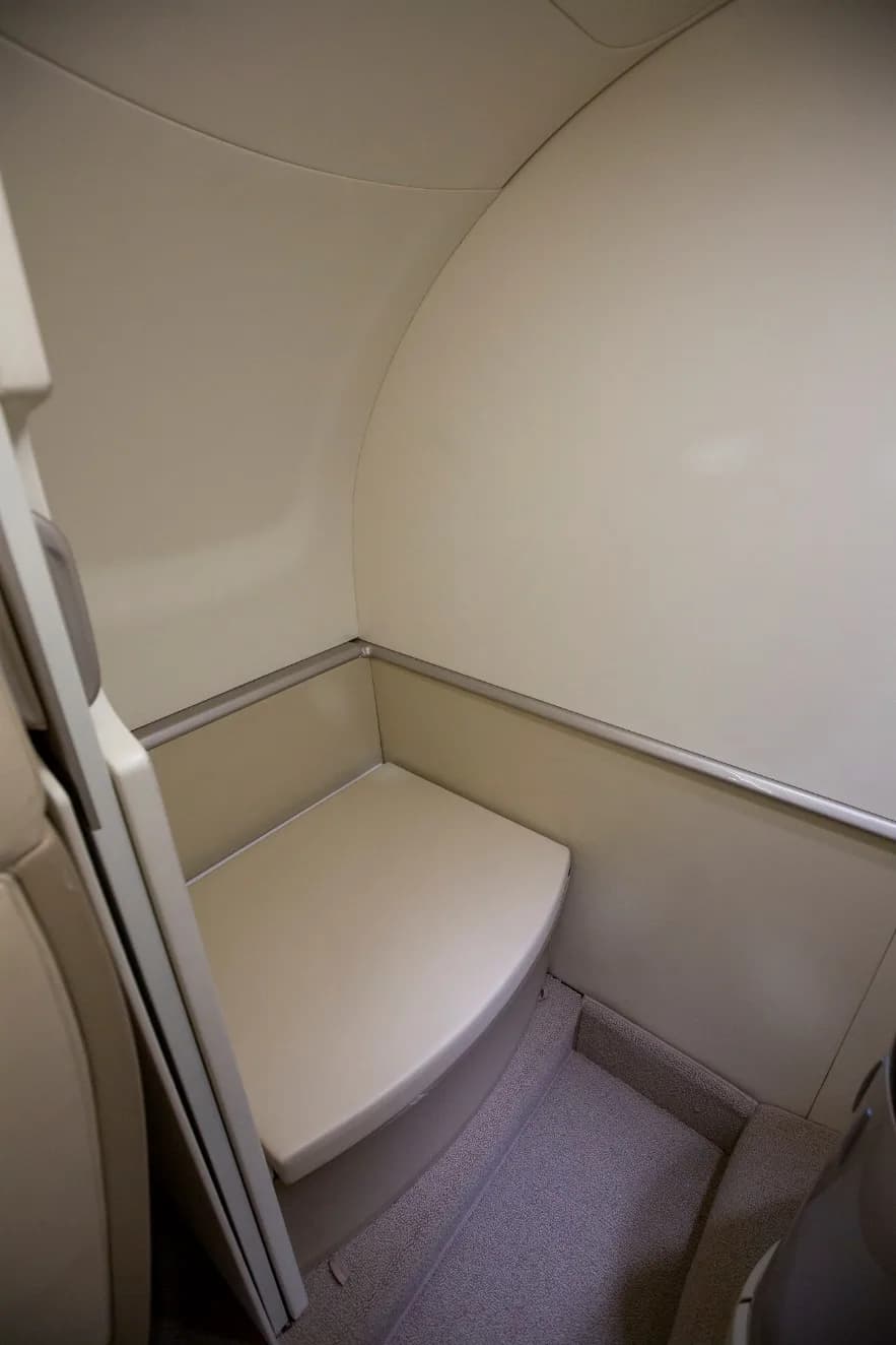 A small, light-colored bench seat or jump seat area within the aircraft's cabin.