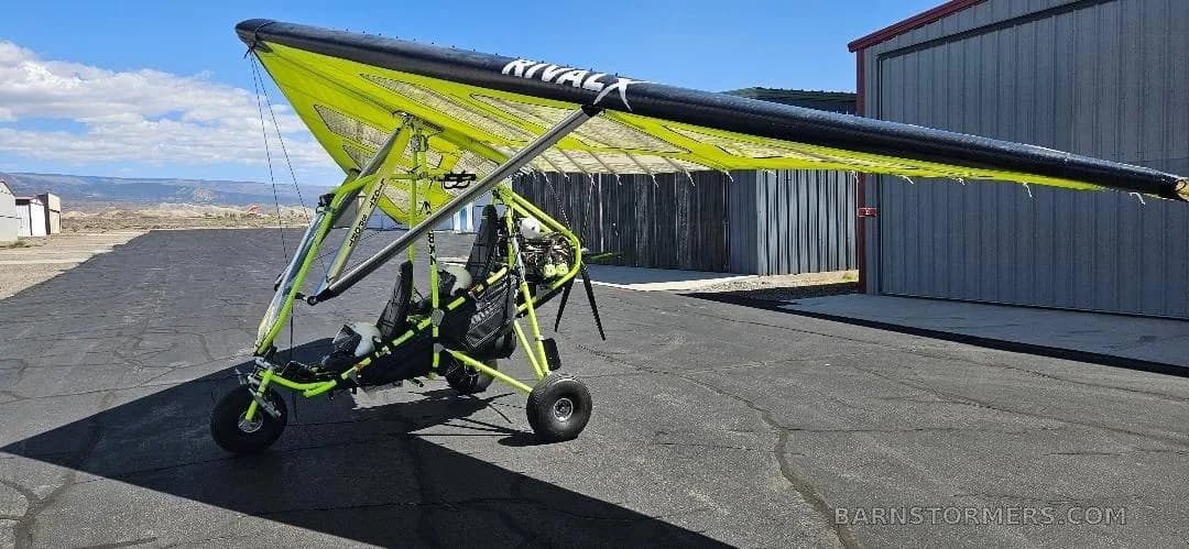 A side view of a yellow and black Revolt ultralight trike parked on an airfield tarmac.