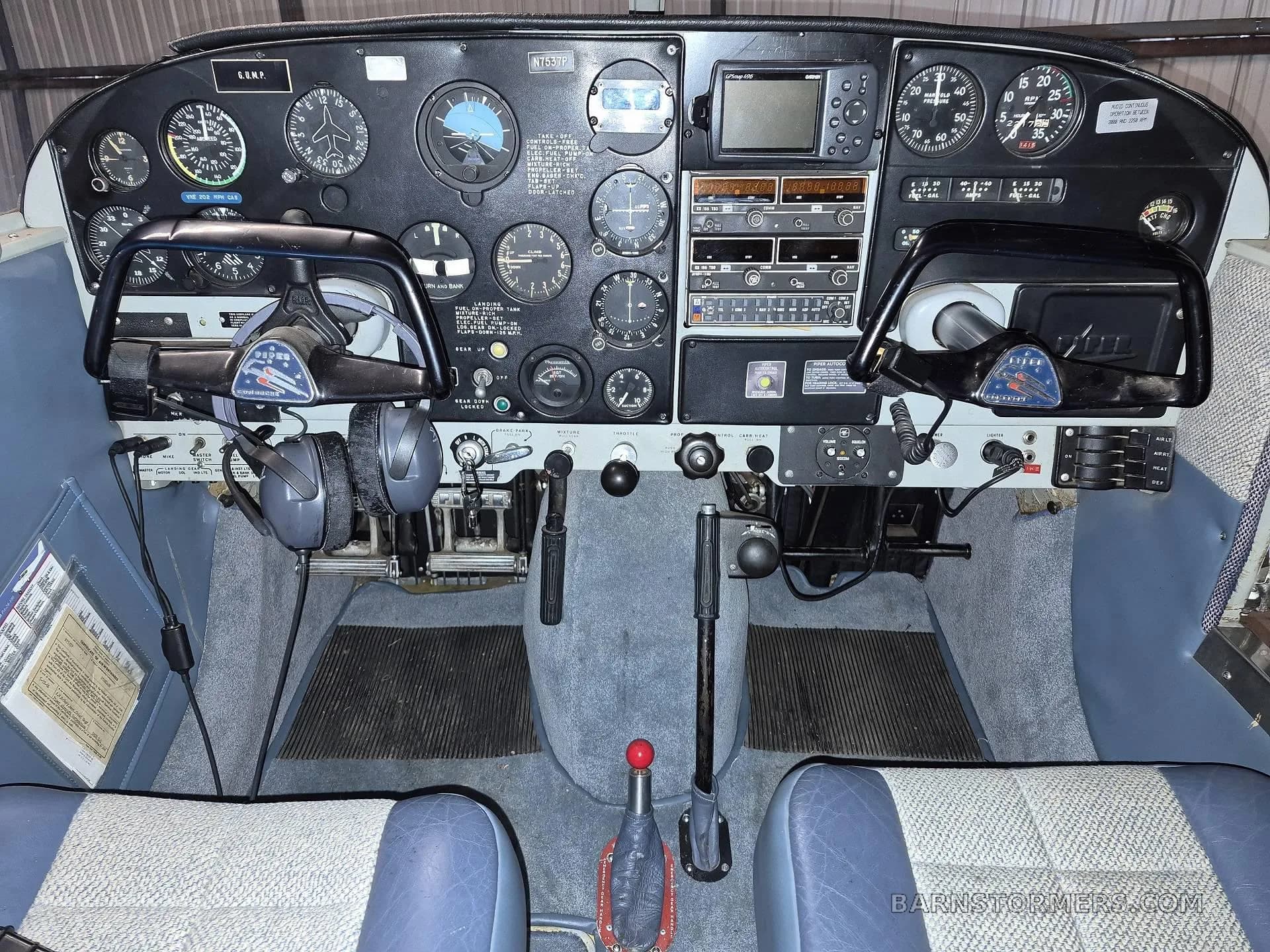 The cockpit of a small aircraft, showing the instrument panel, yokes, and various controls.