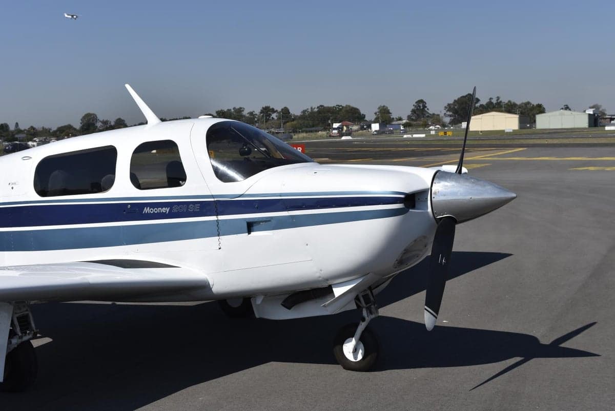Close-up of the nose and propeller of a Mooney M20J 201 SE aircraft.