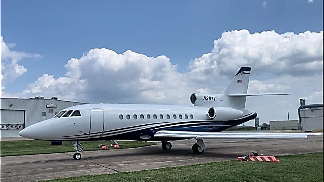 Side view of a white and blue aircraft with tail number N38TY on the tarmac.