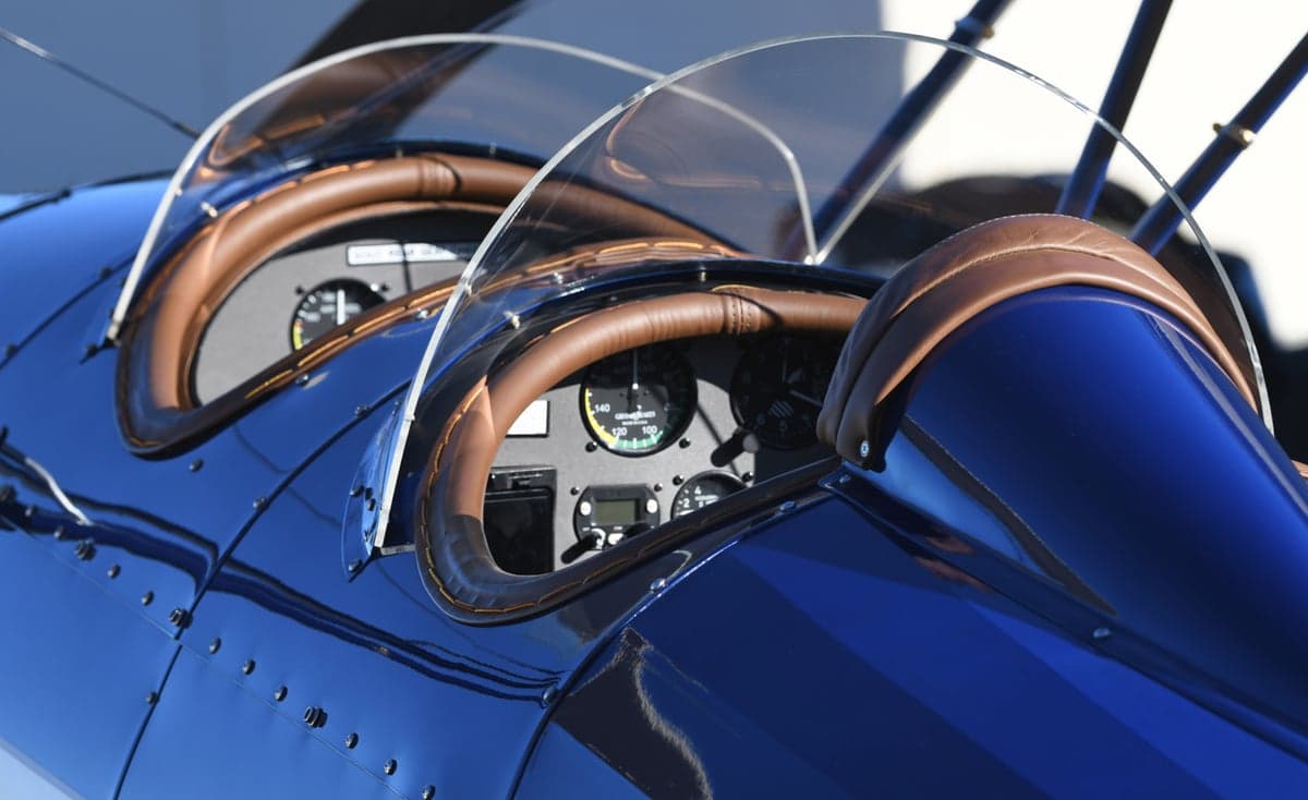 Close-up of the cockpit of a blue biplane, showing the instrument panel and leather trim.