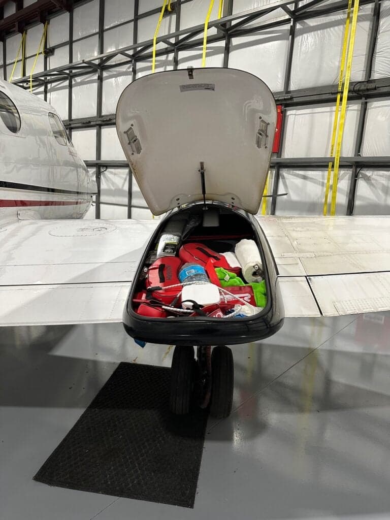 An open cargo pod under the wing of the aircraft, filled with various items.