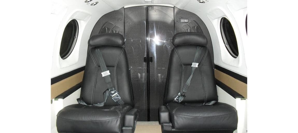 Two black leather seats in the cabin of a Beechcraft King Air.