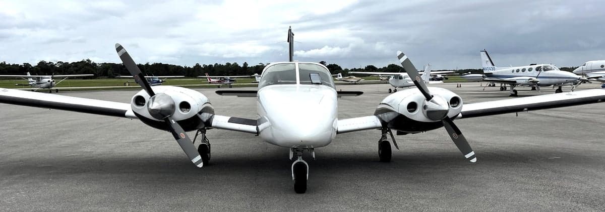 Front view of a Piper Seneca II aircraft with a white and black paint scheme parked on the tarmac.