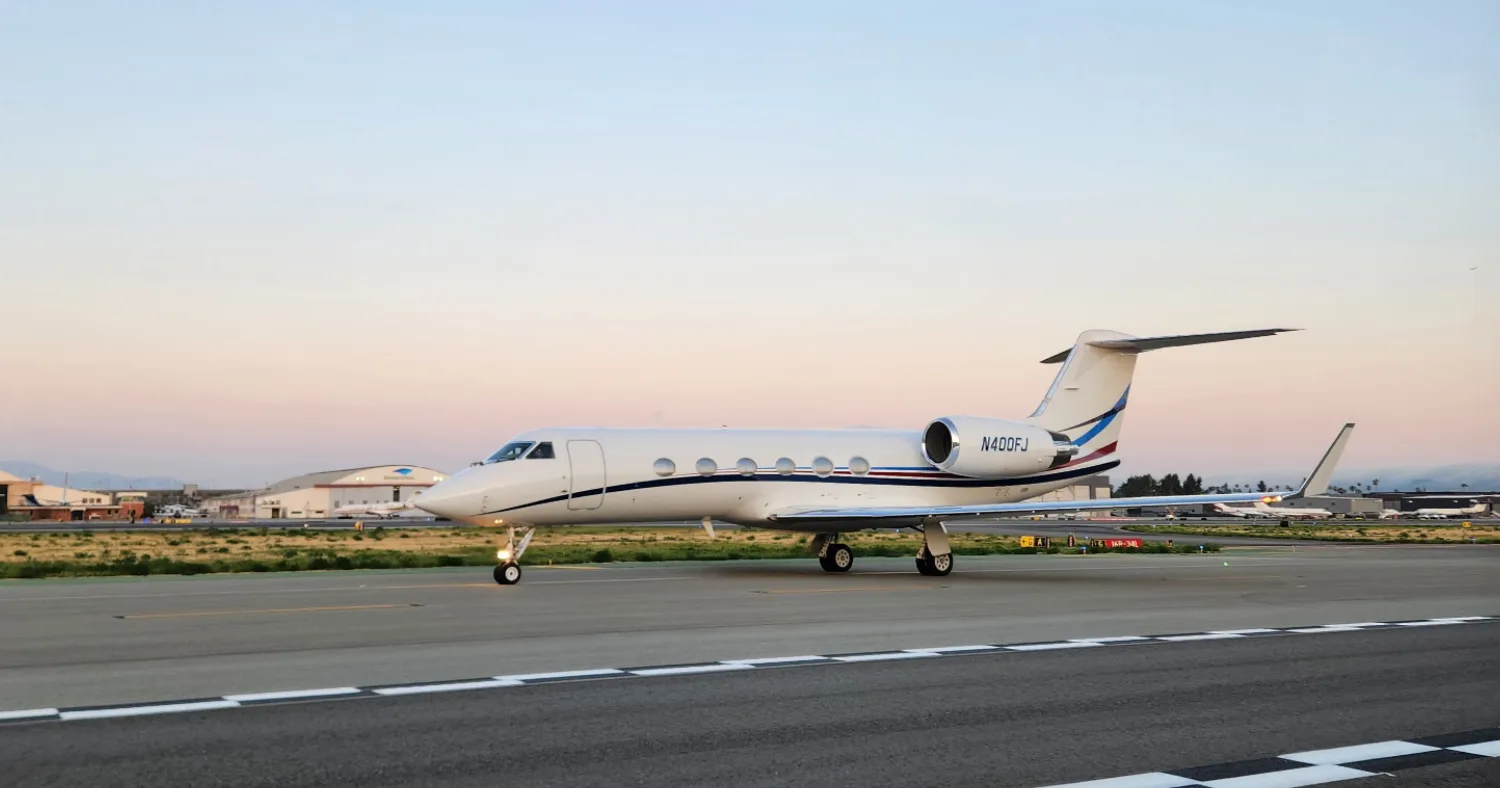 Gulfstream jet with blue and red accents on the runway at dusk.