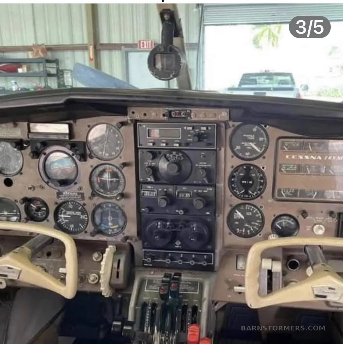 The instrument panel of a Cessna aircraft, showing various gauges, radios, and controls, with a view outside the windshield.
