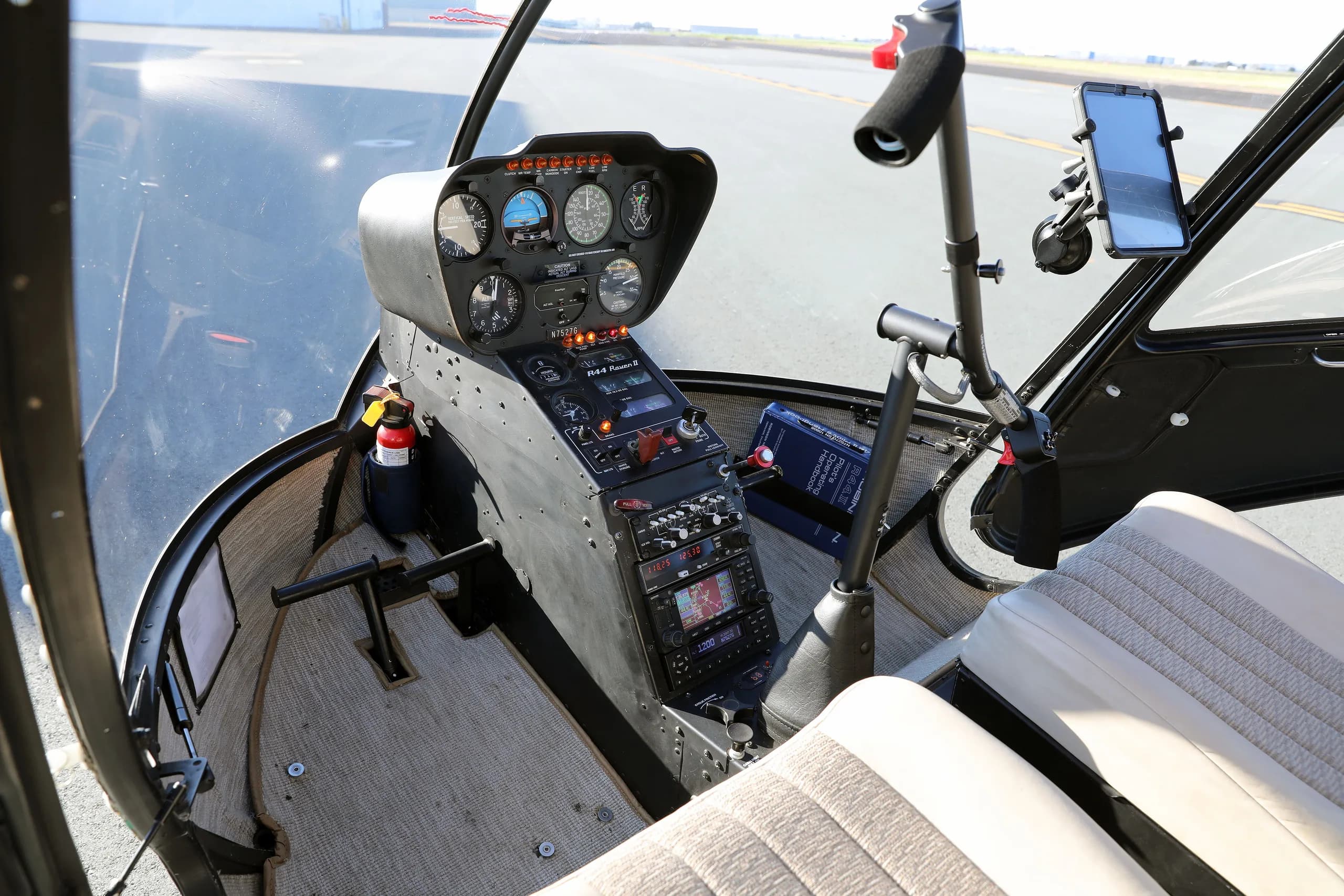 View of the cockpit and front seats of the Robinson R44 Raven II helicopter, showing instruments and controls.