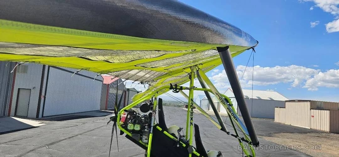 A close-up view of the yellow and black wing and frame of a Revolt ultralight trike.